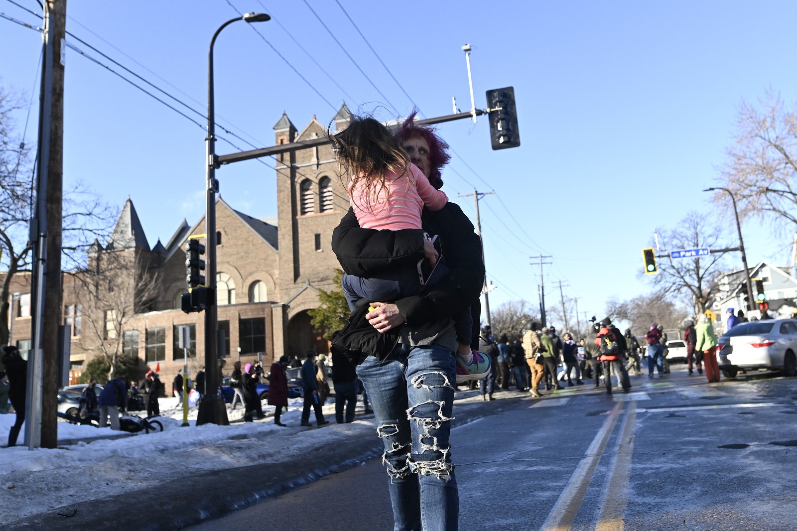 A person carries a child away from an intersection where ICE agents are being confronted by protesters.