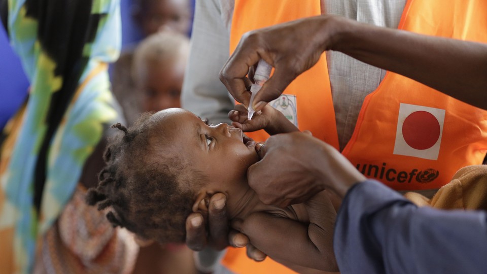 An adult administers an oral vaccine to a baby.