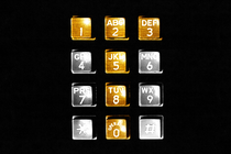 A phone dial with the buttons creating a T colored gold and the others colored silver, with a black background