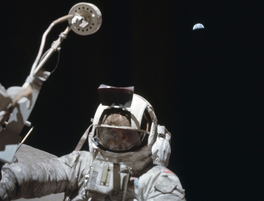 A view, directed upward, of a suited astronaut and a distant Earth in space