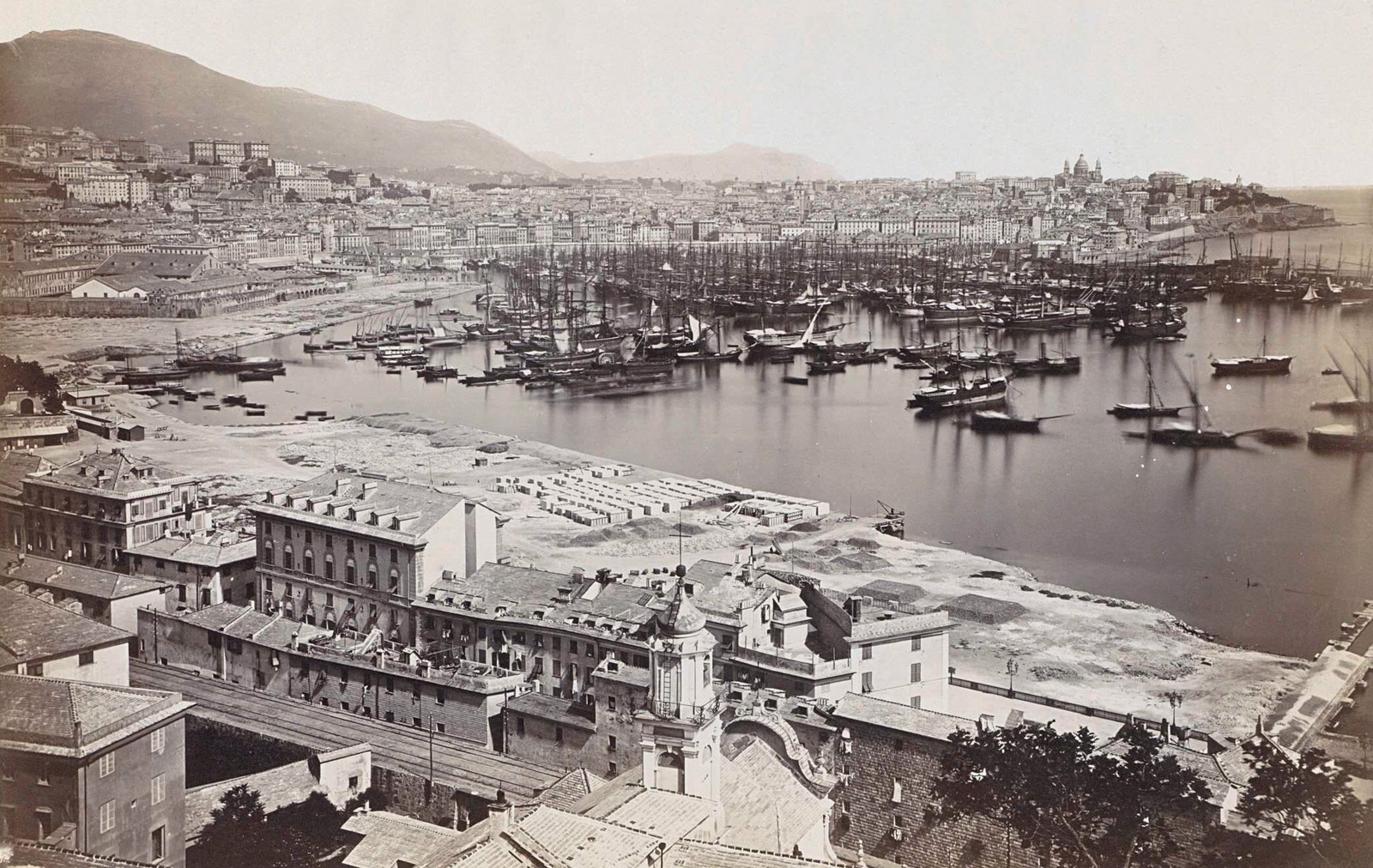 An elevated view of a crowded port in an Italian city in 1876.