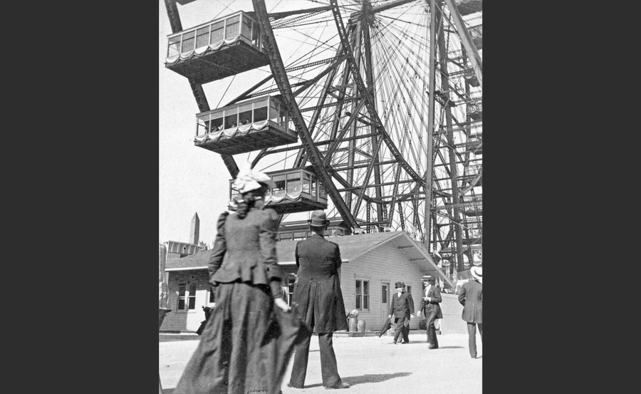 A close view of people at the foot of a large Ferris wheel
