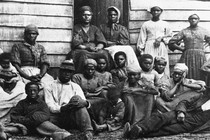 A black-and-white image of Black Americans in front of a cabin