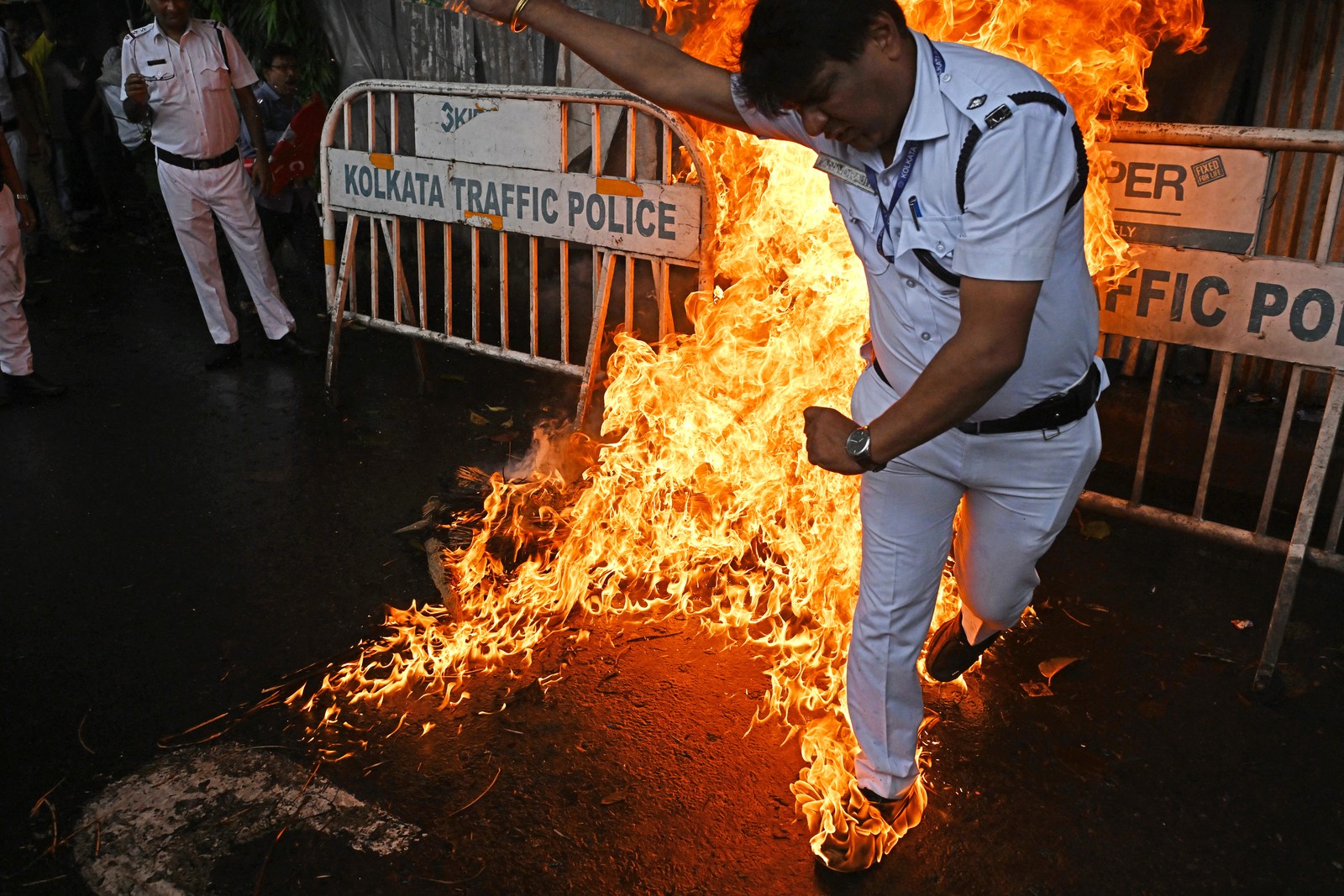 A police officer in a white uniform jumps quickly with their shoes ablaze, after trying to stomp out a fire.