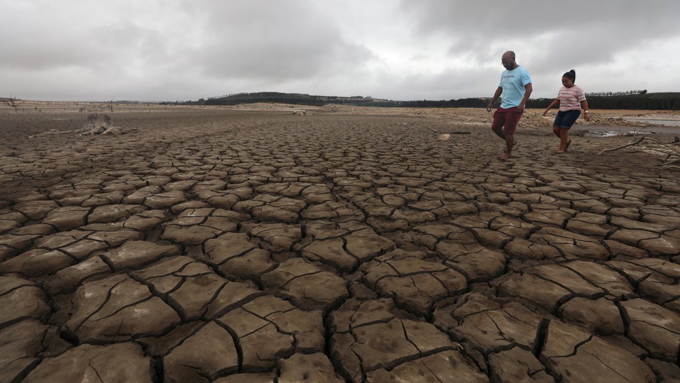 A family negotiates their way through caked mud around a dried up section of the Theewaterskloof dam.