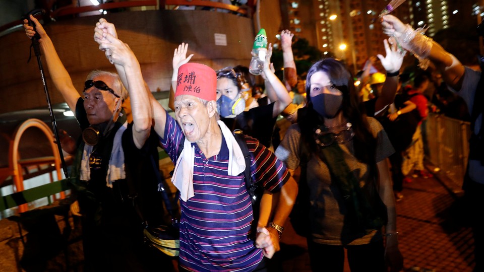 Protesters wearing gas masks and makeshift body armor march in the streets of Hong Kong.