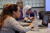 Students sit at laptop computers