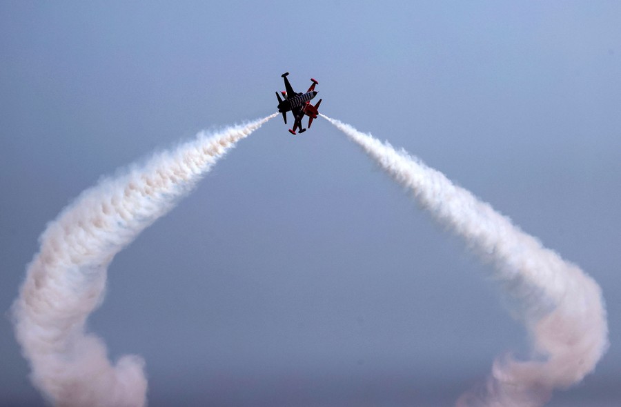 Two jet fighters fly past each other, almost seeming to touch, during an aerobatic show.