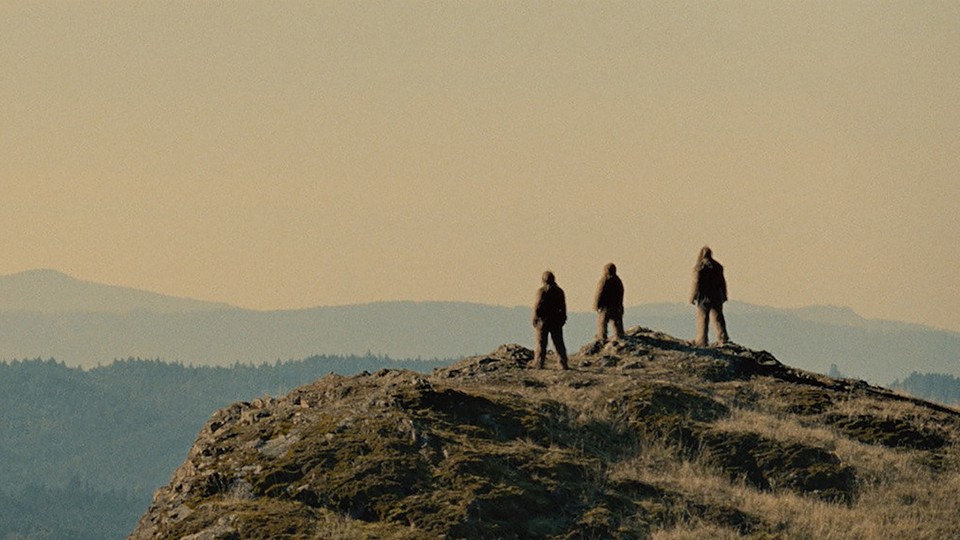 Silhouettes of three Sasquatches on a mountain