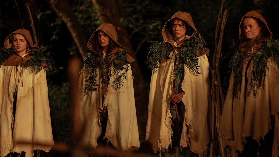 four teenage girls in the woods, wearing robes with leaves on their shoulders