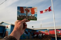 A photo of a Canadian postcard being held up next to a Canadian flag