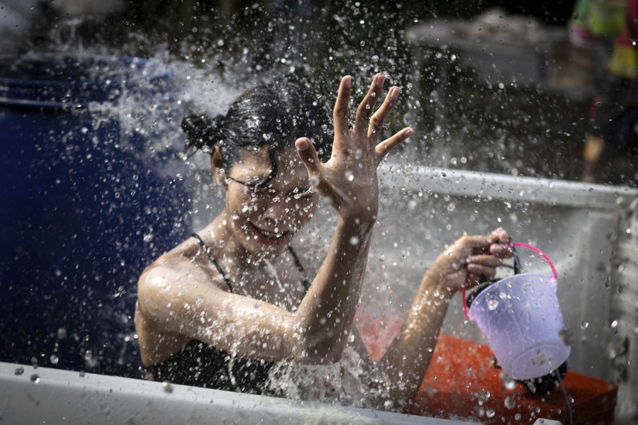 A woman reacts as water is splashed on her.