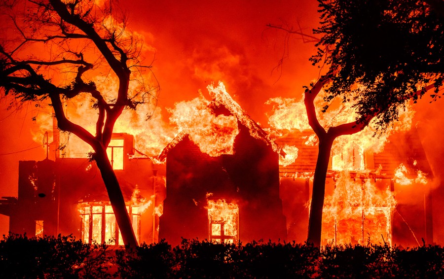 A home is engulfed in flames during a wildfire.