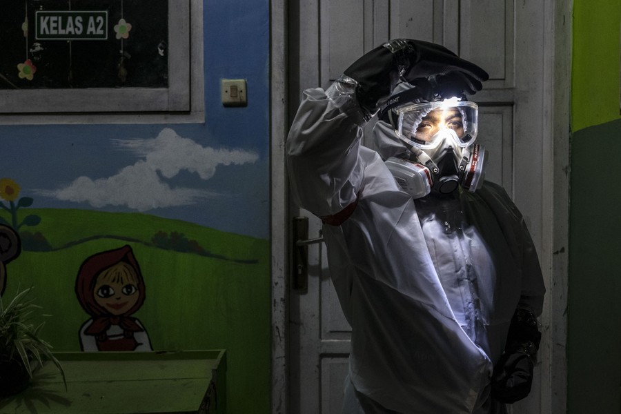 A person wearing protective gear stands outside a door.