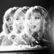 A stylized, black-and-white photo of Taylor Swift singing into a microphone