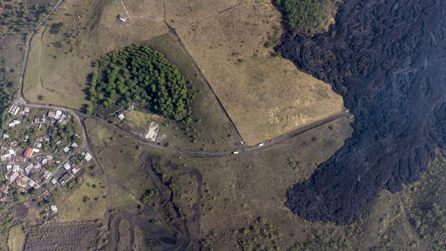 An aerial view of lava flowing near a small village