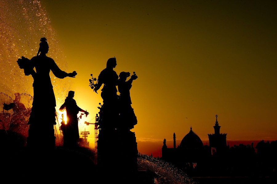 A sunset view of statues in a fountain.