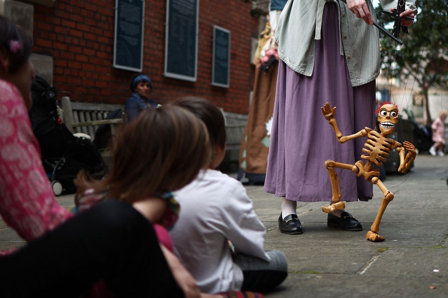 People watch a marionette performance featuring a skeleton puppet.