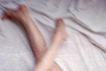 An image of legs on bedsheets