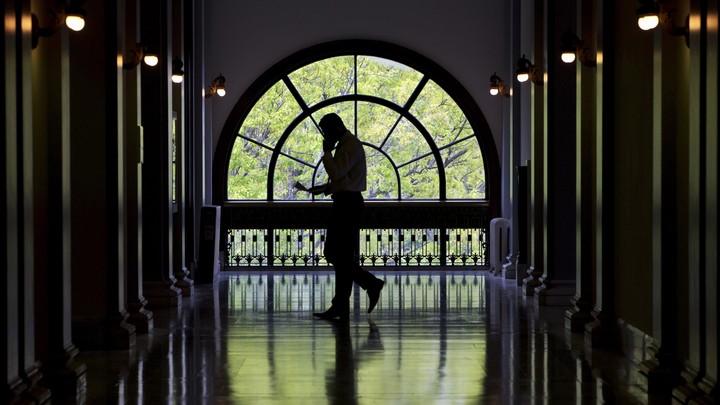 An unidentifiable man walks with a cellphone through a Capitol Hill building.