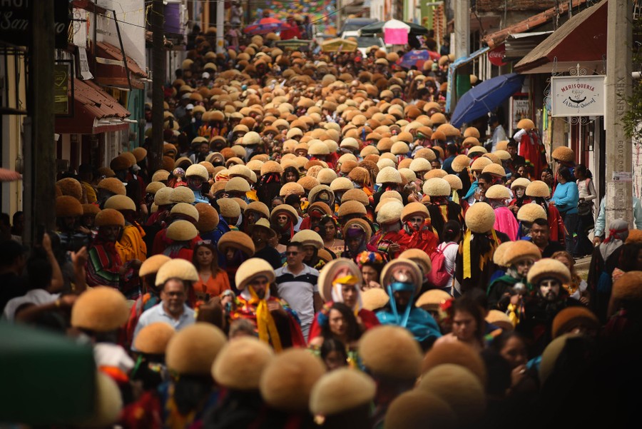 Hundreds of people wearing traditional costumes fill a city street.