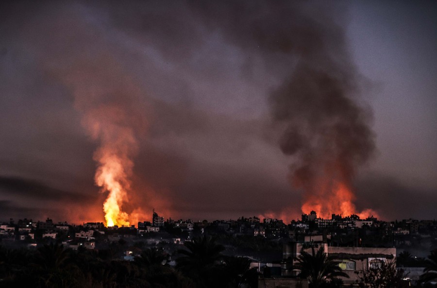 Smoke and flames rise above two different sites among buildings.