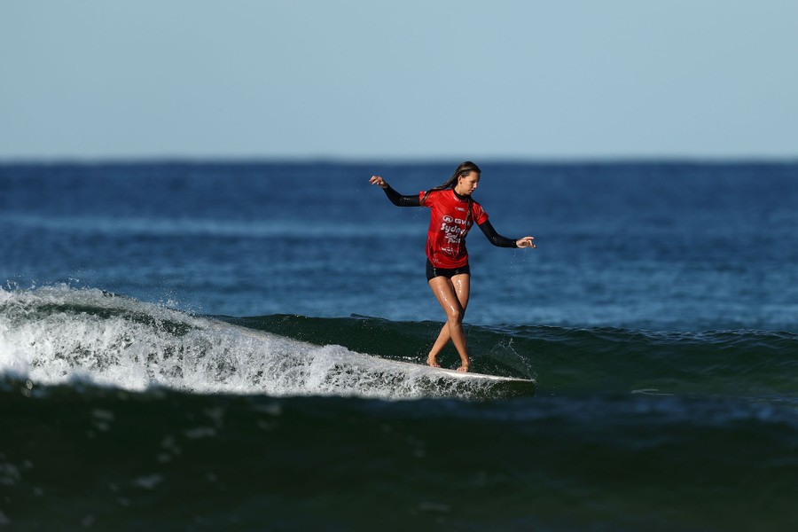 A person rides a wave on a surfboard.