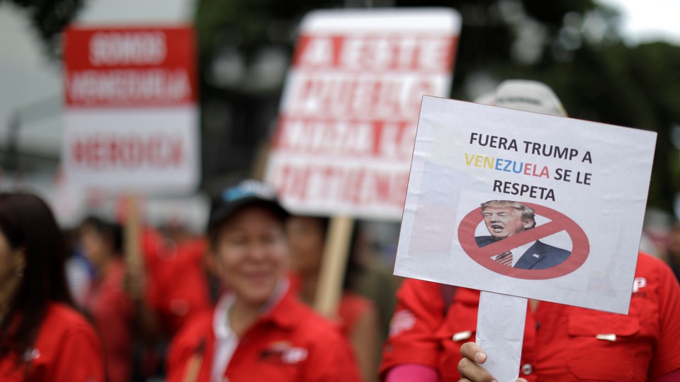 Venezuelan protesters carry a sign against President Trump