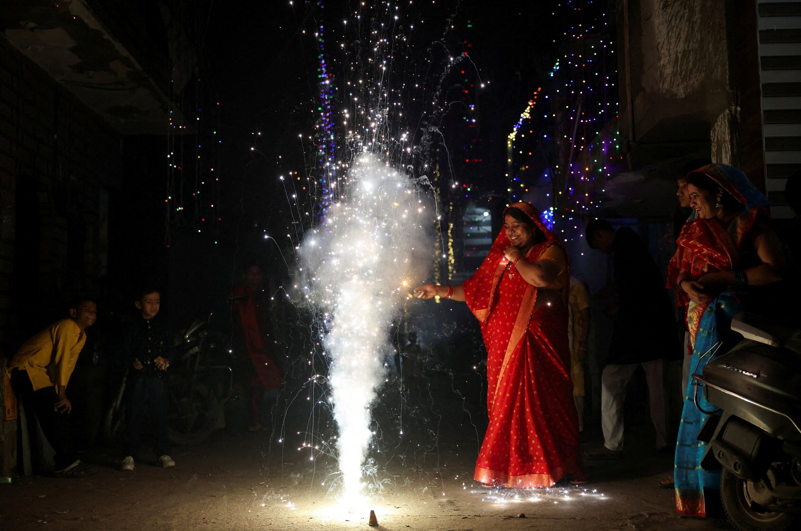 A woman lights fireworks in a street to celebrate Diwali.