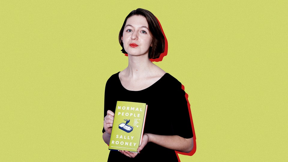 Sally Rooney poses with a copy of her book "Normal People" against a yellow background.