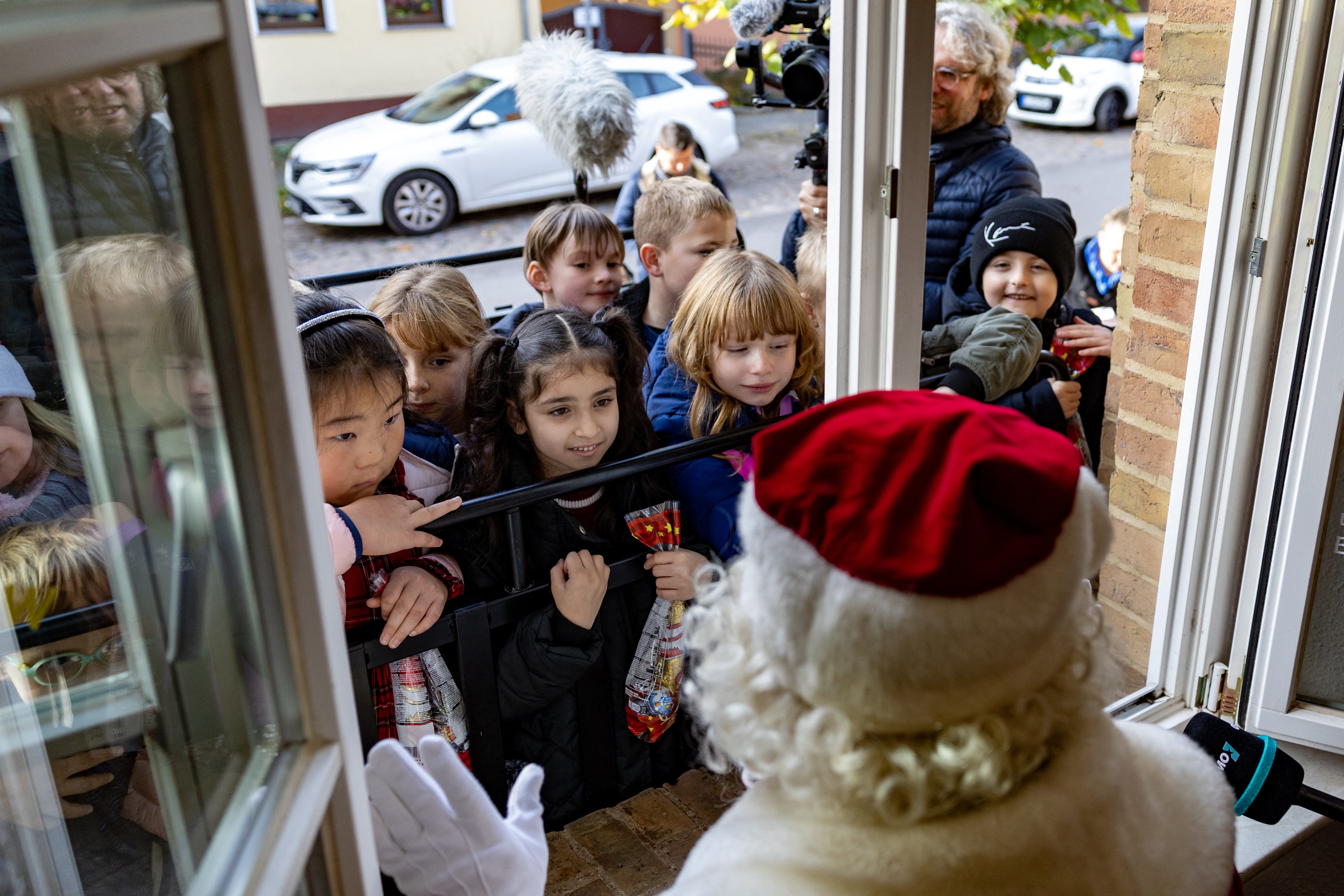 A half-dozen children gather at an open window, greeted by someone dressed as Father Christmas.