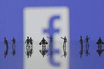 Several human minifigures stand in front of the Facebook logo