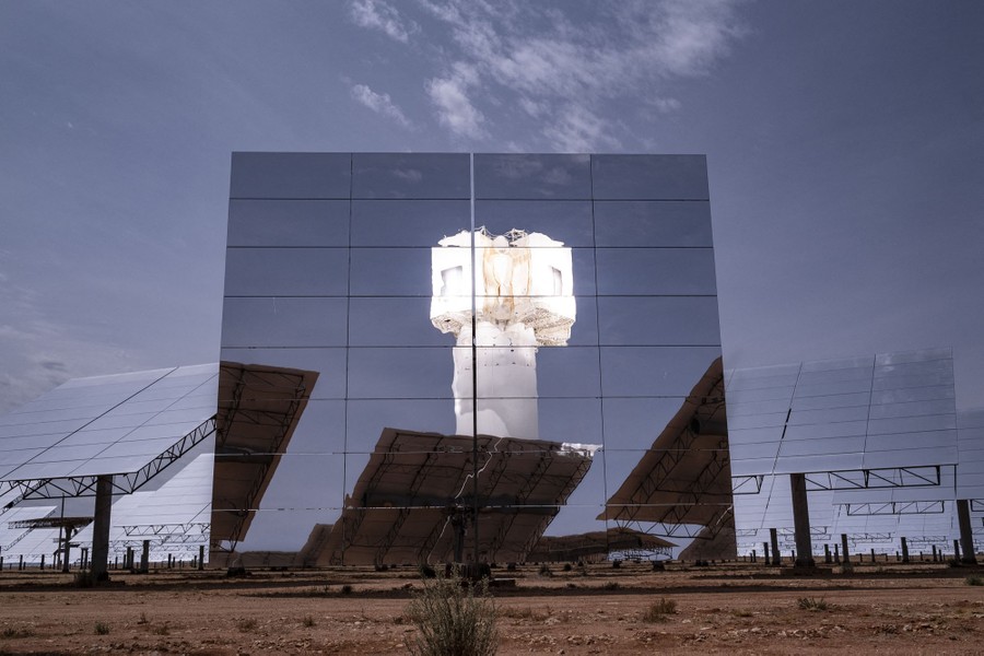 A solar tower is seen, reflected in a large mirror.