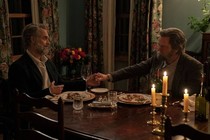 A still from The Last of Us showing two older men holding hands while dining