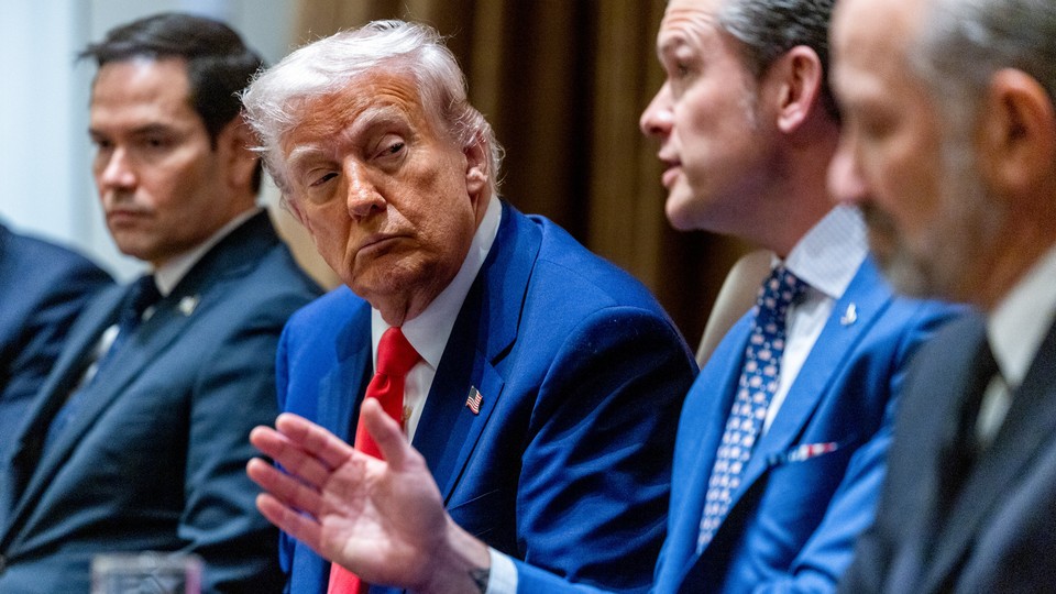 A photo of Pete Hegseth talking as Donald Trump looks on