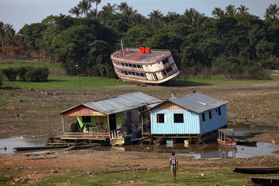 A large boat and two houseboats sit stranded on muddy land.