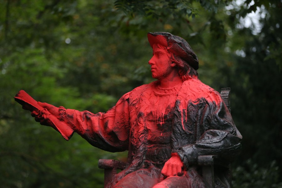 A statue of Christopher Columbus is covered in red paint.