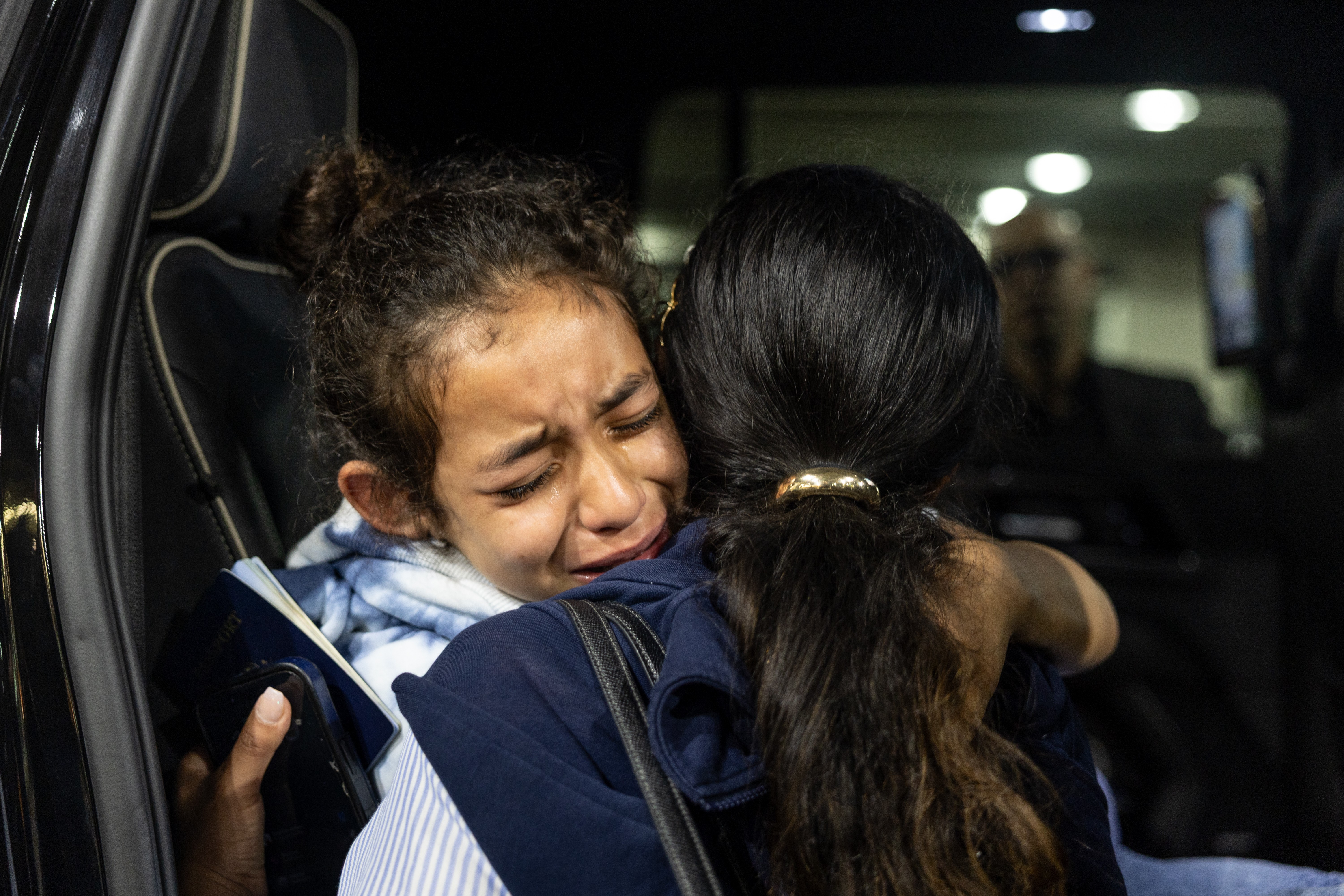 A distraught girl is comforted by her big sister.