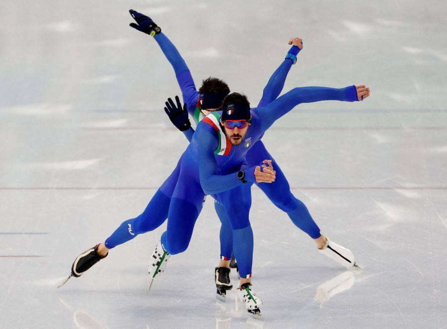 Several speed skaters are seen in action on the ice, skating in a line toward the photographer.