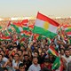 Kurdish people attend a rally and wave Kurdish flags.