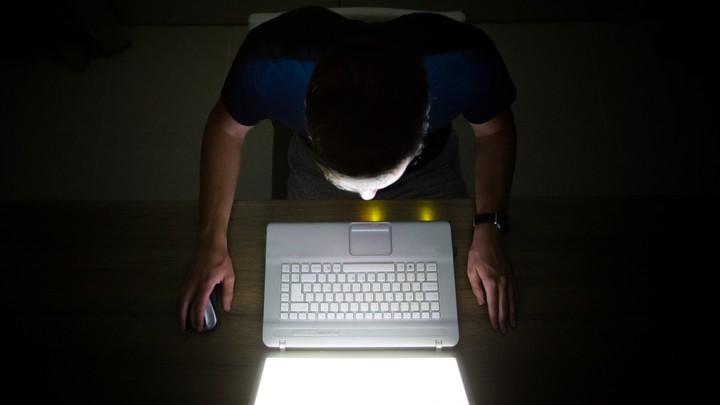A man on his computer in a dark room