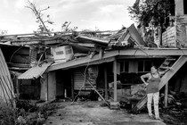 A woman in Puerto Rico stands beside a devastated home.