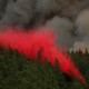 Bright-red fire retardant being dumped over a pine forest