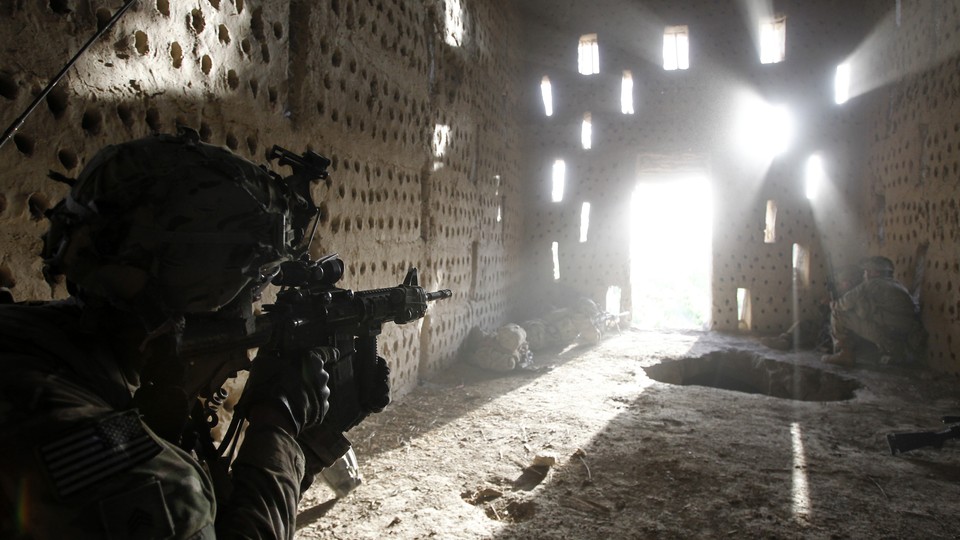 An American soldier points his rifle at a doorway after coming under fire by the Taliban while on patrol in Kandahar province in April 2012.