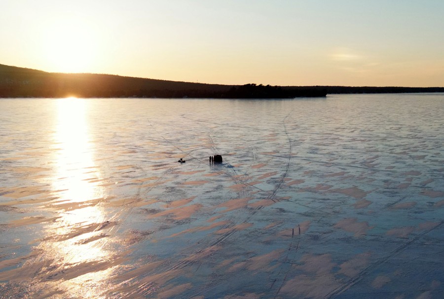 An aerial view of people ice fishing on a large lake