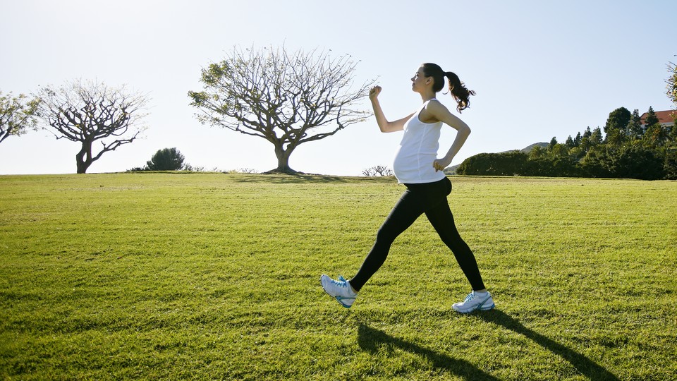 A pregnant woman exercising in a field