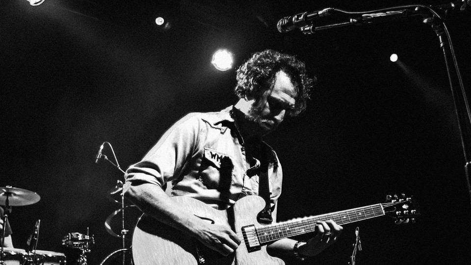 Black-and-white photo of Ryan Miller of Guster playing the guitar