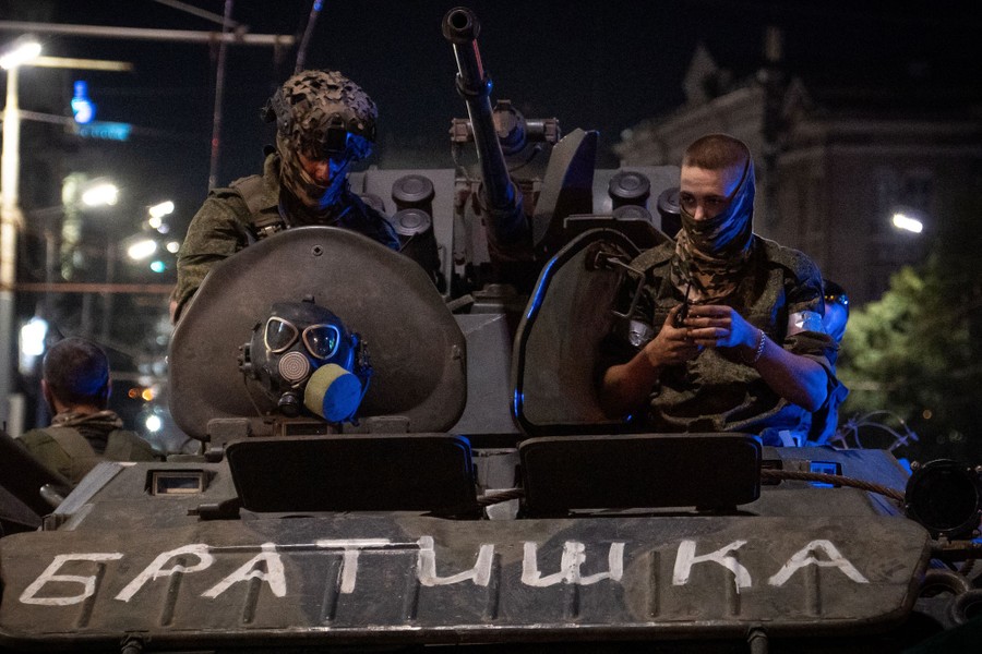 Two soldiers sit in hatches of a military vehicle that has the word "brother" painted on it.