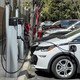 Photo of a row of cars, plugged into charging stations