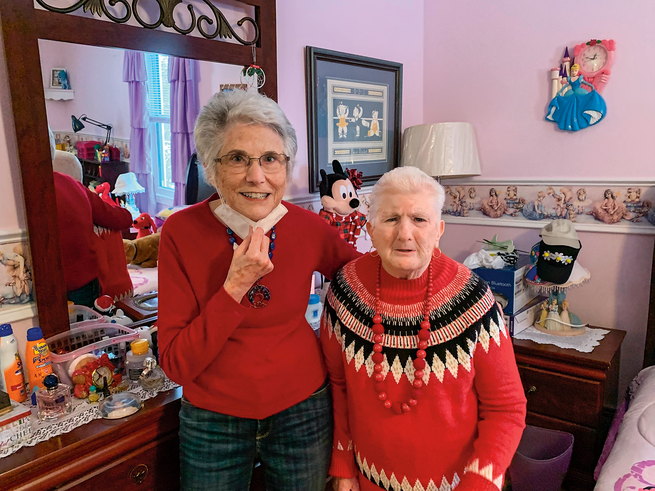 photo of two women in red sweaters standing side by side in bedroom